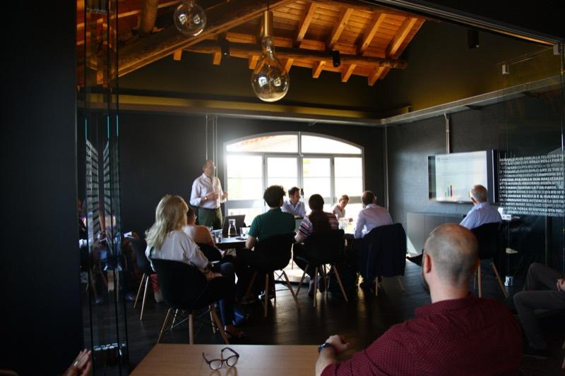 A speaker standing in front of a group seated around tables